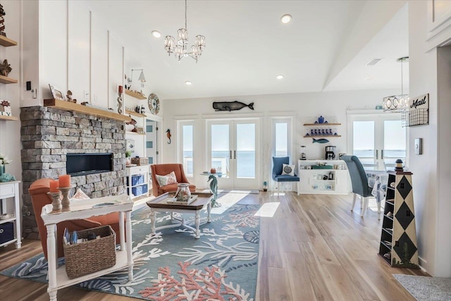 living room featuring french doors, a water view, vaulted ceiling, and light hardwood / wood-style flooring