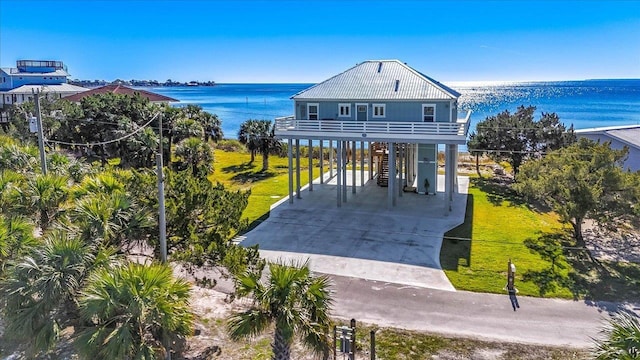 view of front of house with a front lawn, a balcony, a water view, and a carport