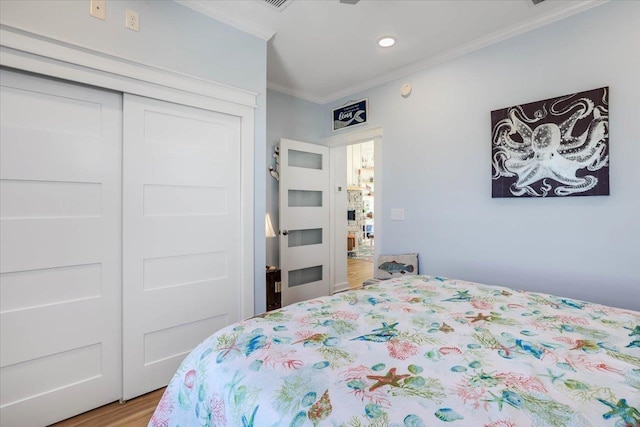 bedroom with crown molding, a closet, and light hardwood / wood-style floors