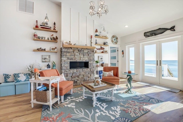 living room featuring french doors, a water view, a chandelier, and light hardwood / wood-style flooring