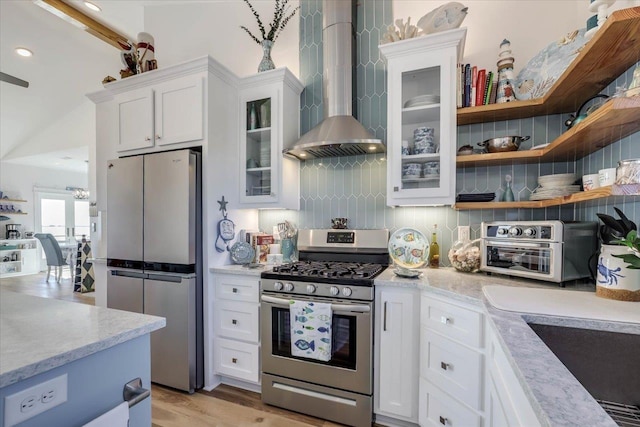 kitchen featuring wall chimney exhaust hood, light hardwood / wood-style floors, decorative backsplash, white cabinets, and appliances with stainless steel finishes