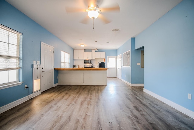 kitchen featuring white cabinetry, appliances with stainless steel finishes, kitchen peninsula, and light wood-type flooring