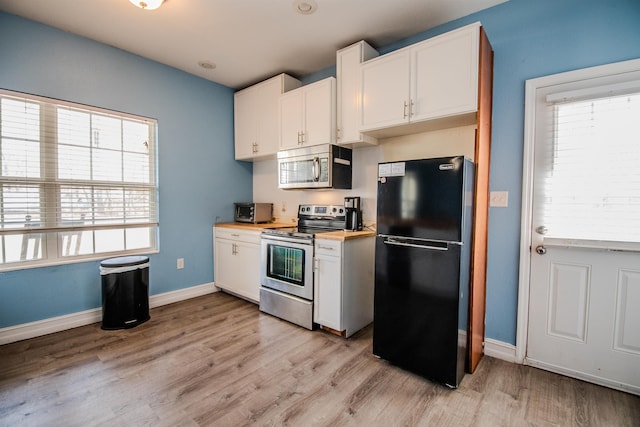kitchen with butcher block counters, light hardwood / wood-style flooring, stainless steel appliances, and white cabinets