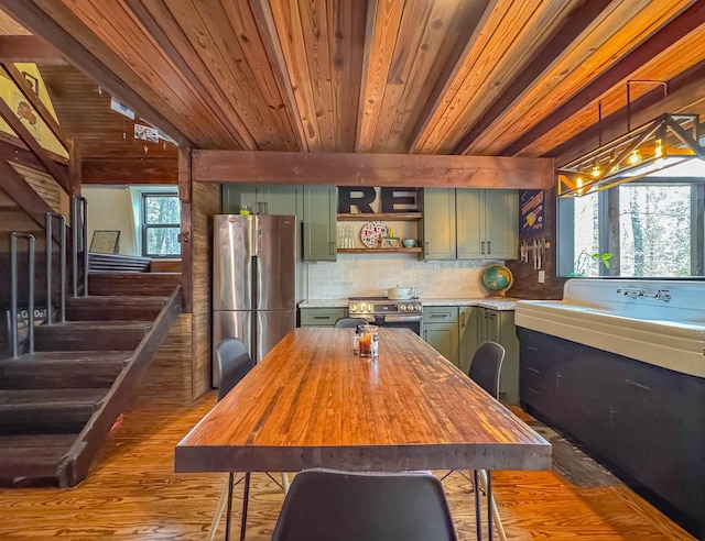 kitchen featuring appliances with stainless steel finishes, hanging light fixtures, a wealth of natural light, green cabinets, and tasteful backsplash