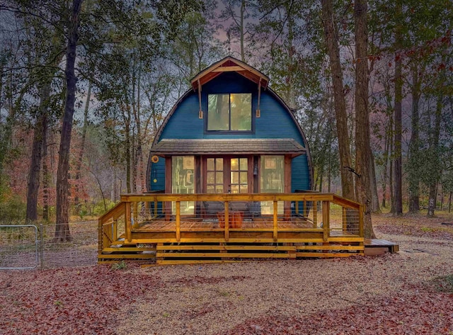 back house at dusk featuring a wooden deck