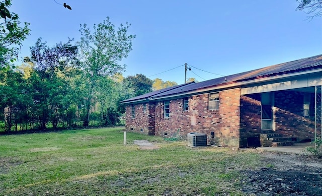 view of side of home with central AC, crawl space, a yard, entry steps, and metal roof