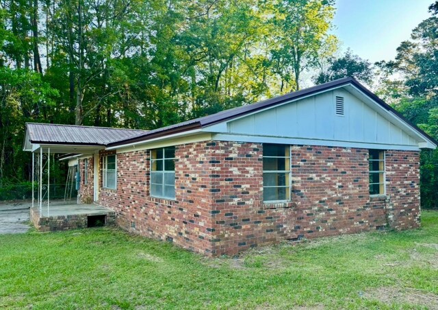 view of side of home with brick siding, a yard, and metal roof