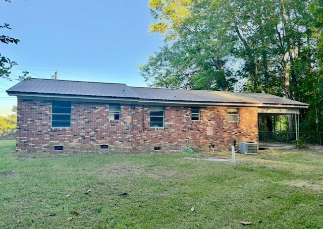 rear view of property with central AC unit, a yard, metal roof, crawl space, and brick siding