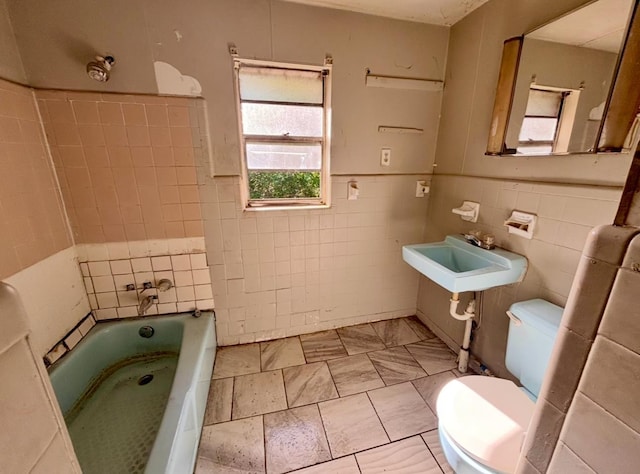 bathroom featuring a sink, a bathing tub, tile walls, toilet, and a shower
