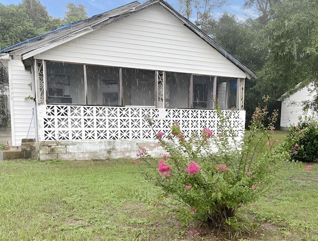 view of property exterior with a lawn and a sunroom