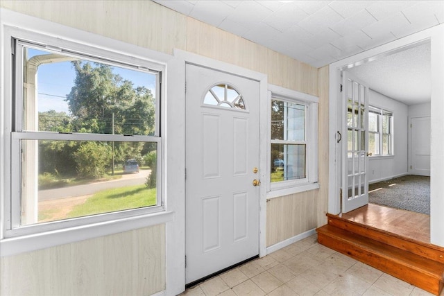 entrance foyer featuring wood walls and a healthy amount of sunlight