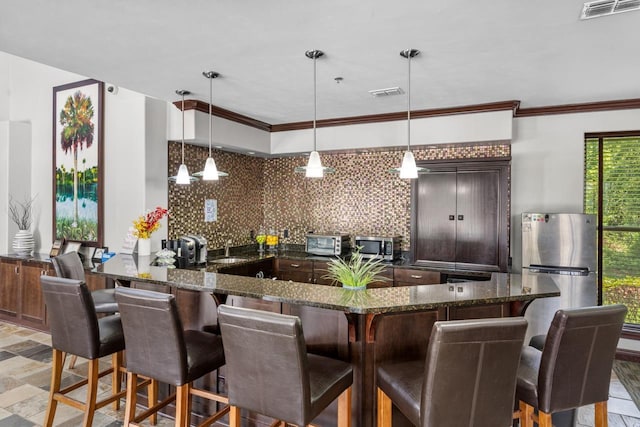 kitchen with decorative light fixtures, tasteful backsplash, stainless steel appliances, crown molding, and dark brown cabinets