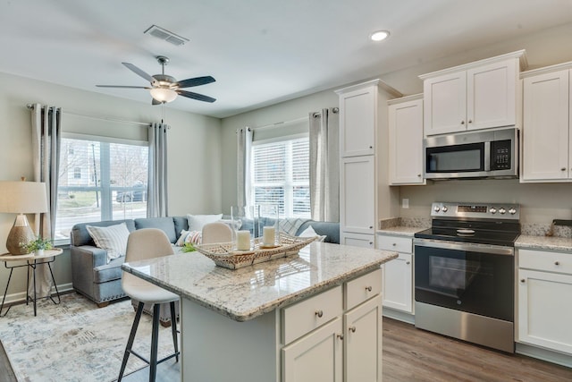 kitchen with white cabinetry, appliances with stainless steel finishes, a kitchen breakfast bar, and a center island