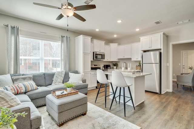 living room featuring sink, ceiling fan, and light hardwood / wood-style flooring