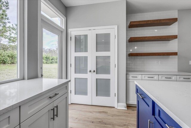 kitchen featuring tasteful backsplash, blue cabinets, and light wood-style floors