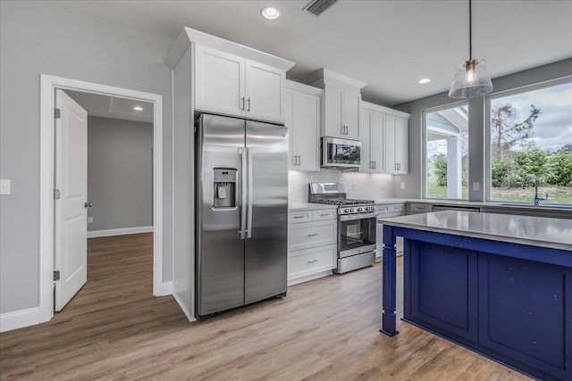 kitchen featuring stainless steel appliances, visible vents, white cabinetry, a sink, and light wood-type flooring