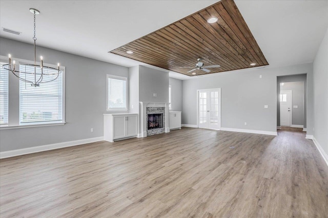 unfurnished living room with a fireplace, wood finished floors, visible vents, and baseboards