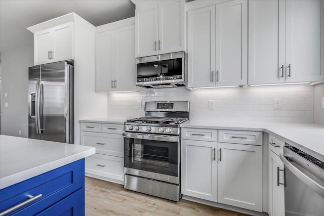 kitchen with decorative backsplash, light wood-style flooring, appliances with stainless steel finishes, light countertops, and white cabinetry