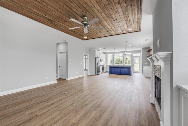 unfurnished living room with baseboards, wood ceiling, light wood-type flooring, a fireplace, and ceiling fan with notable chandelier