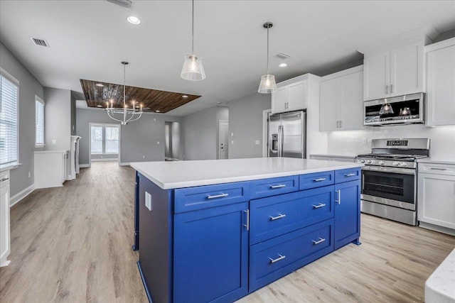 kitchen featuring stainless steel appliances, blue cabinets, light countertops, and visible vents