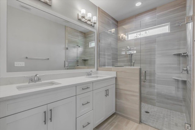 full bath featuring double vanity, a shower stall, and a sink