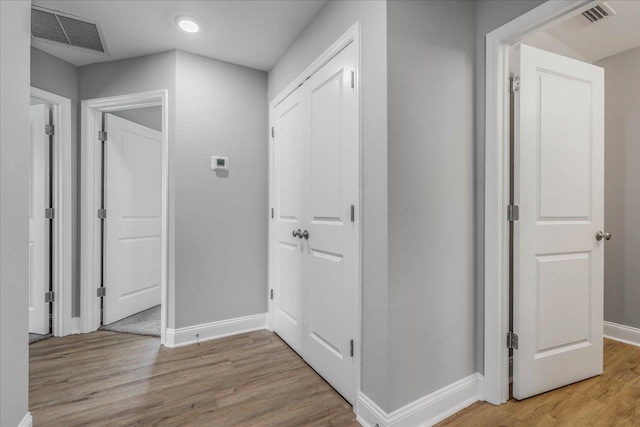 corridor featuring light wood-style flooring, visible vents, and baseboards