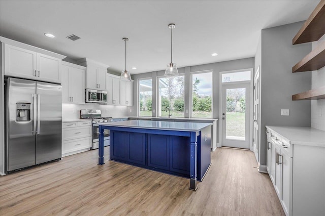 kitchen with stainless steel appliances, a kitchen island, visible vents, white cabinets, and open shelves