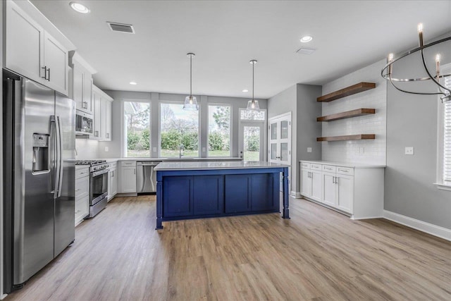 kitchen with stainless steel appliances, light countertops, visible vents, a kitchen island, and light wood-type flooring