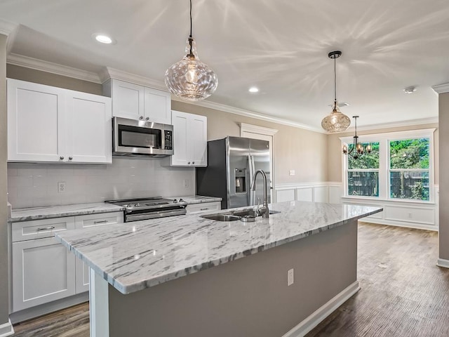 kitchen featuring stainless steel appliances, sink, a center island with sink, white cabinetry, and hanging light fixtures