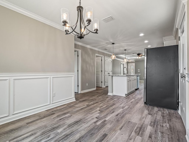 kitchen with pendant lighting, white cabinets, ornamental molding, an island with sink, and wood-type flooring