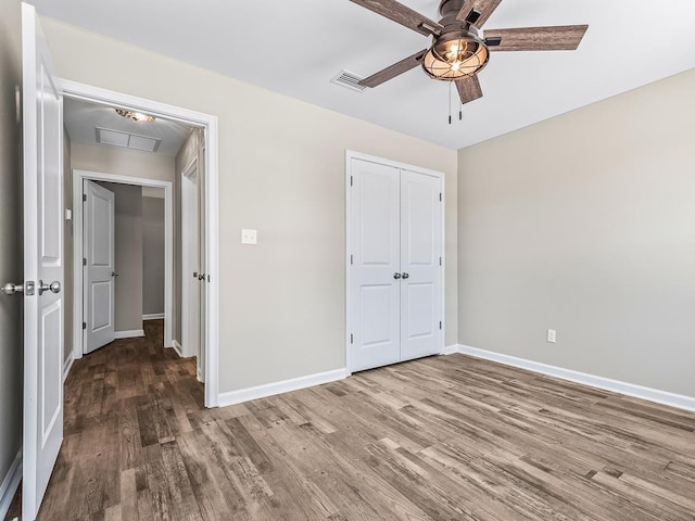 unfurnished bedroom with a closet, hardwood / wood-style flooring, and ceiling fan