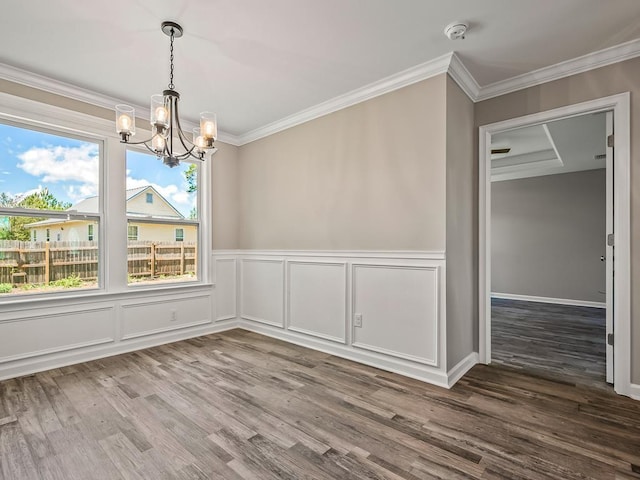 unfurnished dining area featuring crown molding, hardwood / wood-style floors, and an inviting chandelier