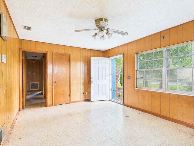 302 Goff St, Perry, FL 32347 - spare room with wood walls, tile patterned floors, ceiling fan, and a textured ceiling