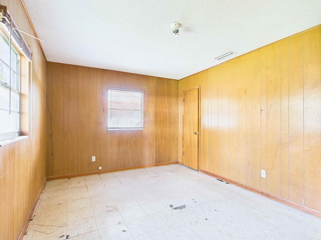 302 Goff St, Perry, FL 32347 - spare room featuring tile patterned floors, wooden walls, a textured ceiling, and fire sprinkler in ceiling