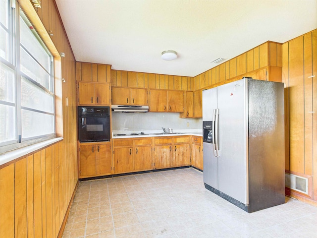 302 Goff St, Perry, FL 32347 - kitchen featuring stainless steel refrigerator with ice dispenser, black oven, under cabinet range hood, light countertops, and brown cabinets