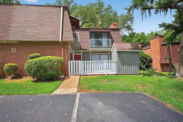 2965 N Shamrock, Tallahassee, FL 32309 - view of property with mansard roof, a front lawn, brick siding, a balcony, and a shingled roof