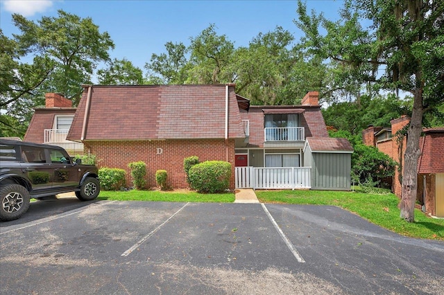 2965 N Shamrock, Tallahassee, FL 32309 - view of front of house featuring mansard roof, a chimney, uncovered parking, and brick siding