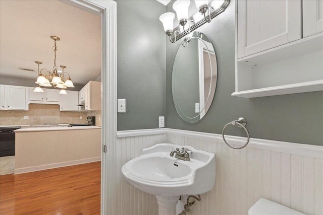 2965 N Shamrock, Tallahassee, FL 32309 - bathroom featuring a chandelier, wainscoting, wood finished floors, and tasteful backsplash