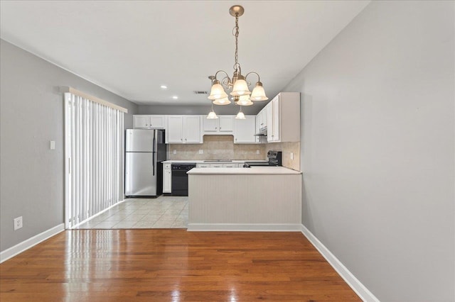 2965 N Shamrock, Tallahassee, FL 32309 - kitchen featuring black appliances, a chandelier, backsplash, light wood-style flooring, and a peninsula