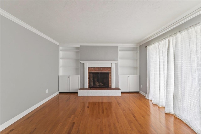 2965 N Shamrock, Tallahassee, FL 32309 - unfurnished living room featuring wood finished floors, built in shelves, ornamental molding, and a brick fireplace