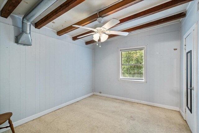unfurnished room featuring beamed ceiling, wooden walls, light carpet, and ceiling fan