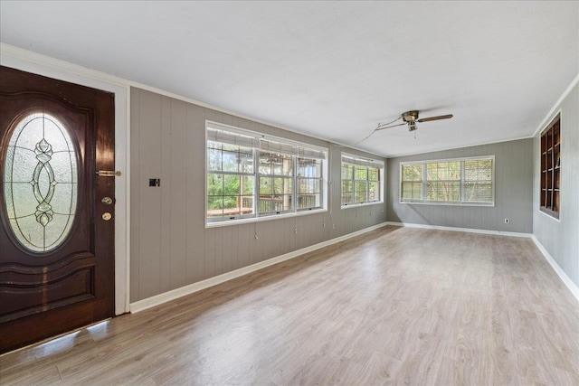 entryway featuring light hardwood / wood-style floors, ceiling fan, a healthy amount of sunlight, and wooden walls