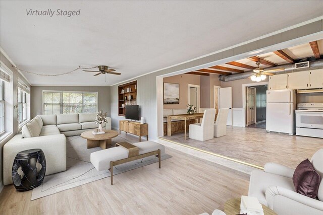 living room with ornamental molding, light wood-type flooring, beamed ceiling, and ceiling fan