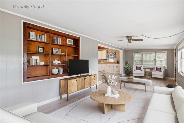 living room with ceiling fan, wooden walls, light hardwood / wood-style floors, and crown molding