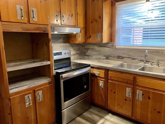 1915 Sunset Ln, Tallahassee, FL 32303 - kitchen featuring stainless steel range with electric stovetop, under cabinet range hood, brown cabinetry, and light countertops