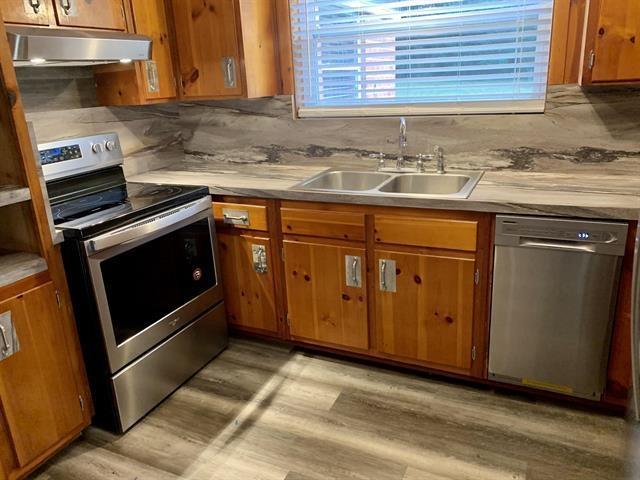 1915 Sunset Ln, Tallahassee, FL 32303 - kitchen featuring appliances with stainless steel finishes, under cabinet range hood, light wood-style flooring, and brown cabinetry