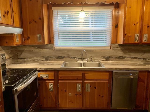 1915 Sunset Ln, Tallahassee, FL 32303 - kitchen with appliances with stainless steel finishes, under cabinet range hood, brown cabinetry, and light countertops