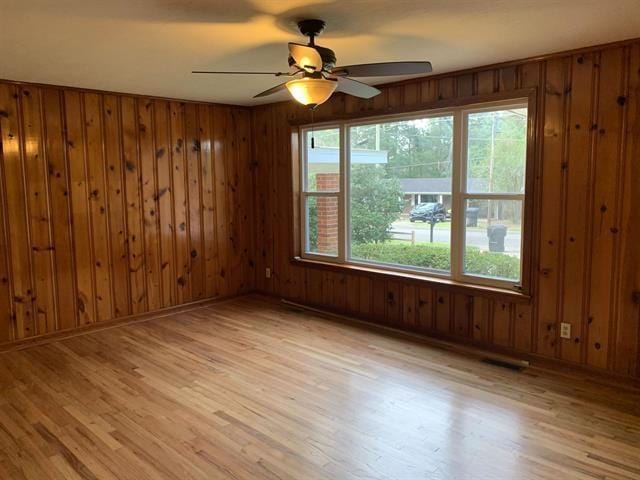 1915 Sunset Ln, Tallahassee, FL 32303 - unfurnished room with ceiling fan, healthy amount of natural light, light wood finished floors, and wood walls