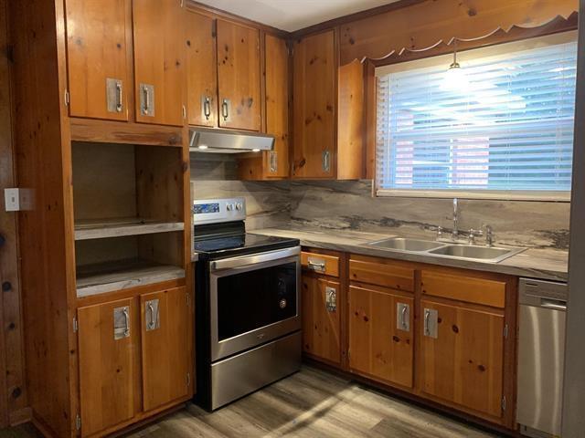 1915 Sunset Ln, Tallahassee, FL 32303 - kitchen with stainless steel appliances, under cabinet range hood, brown cabinets, and light wood-type flooring