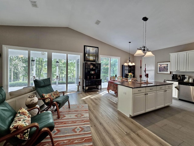 kitchen with white cabinets, dark countertops, visible vents, stainless steel dishwasher, and light wood-type flooring